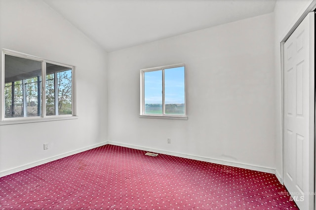 carpeted empty room with vaulted ceiling