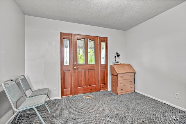 foyer entrance with a textured ceiling and carpet floors