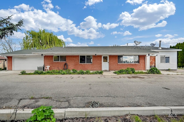 ranch-style home featuring central AC unit and a garage