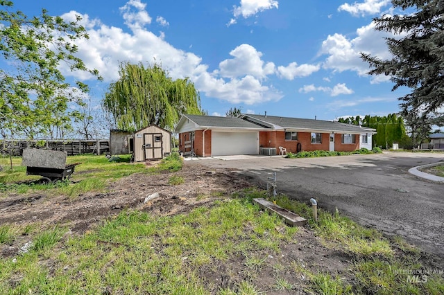 ranch-style home featuring a garage, cooling unit, and a shed