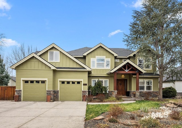 craftsman inspired home with a garage, fence, stone siding, driveway, and board and batten siding