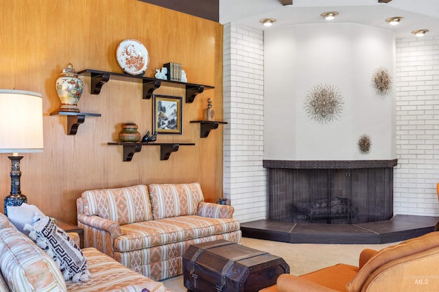 living room with brick wall, carpet, and a tile fireplace