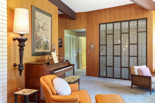 living area with carpet, beam ceiling, a textured ceiling, and wooden walls