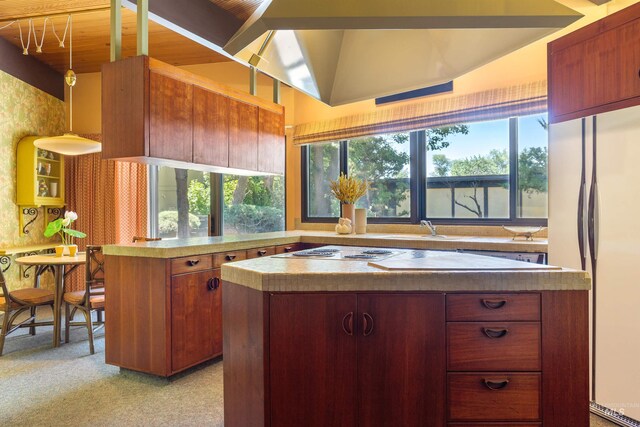 kitchen with light carpet, vaulted ceiling, gas cooktop, decorative light fixtures, and stainless steel fridge