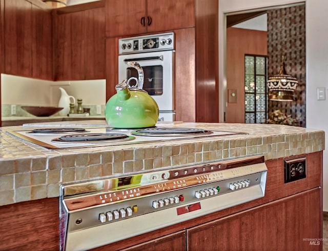 room details featuring hardwood / wood-style flooring, white double oven, and tile countertops