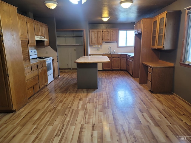 kitchen featuring sink, a kitchen island, electric range, and light hardwood / wood-style flooring