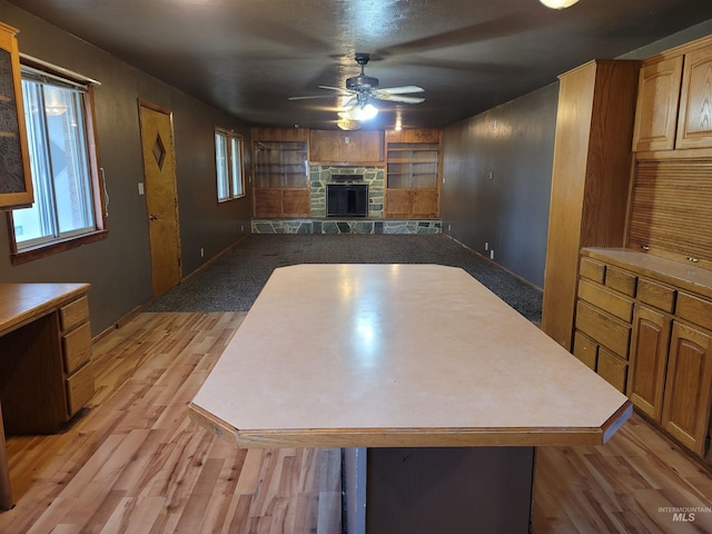 kitchen with light hardwood / wood-style floors, a center island, a fireplace, and ceiling fan