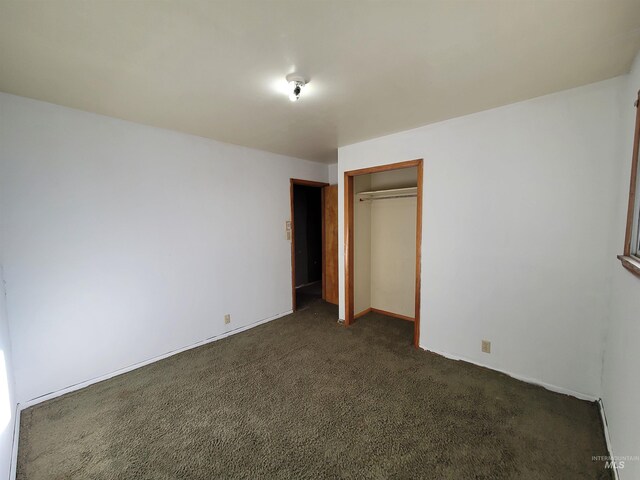 unfurnished bedroom with dark colored carpet and a closet