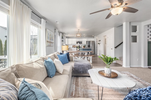 living room featuring stairway, visible vents, baseboards, and a ceiling fan