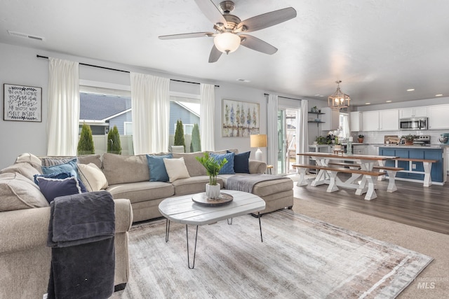 living area with ceiling fan with notable chandelier, visible vents, and light wood-type flooring