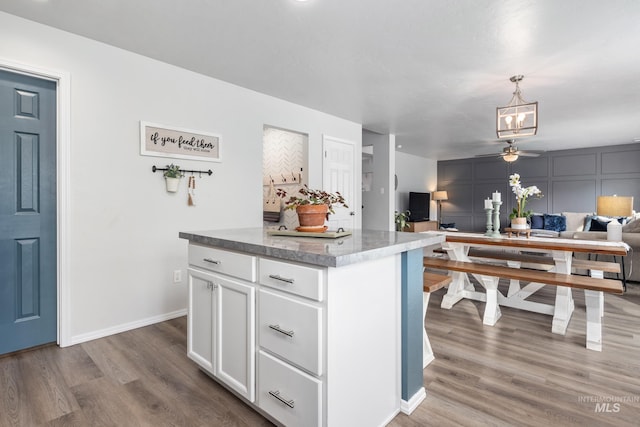 kitchen featuring light wood finished floors, ceiling fan, open floor plan, hanging light fixtures, and white cabinetry