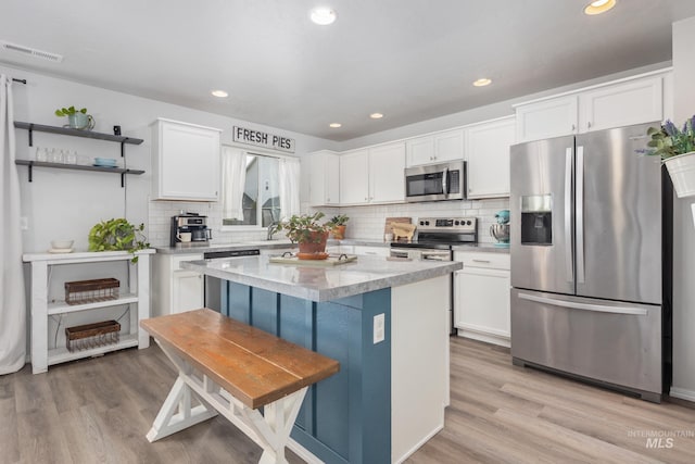 kitchen with white cabinetry, light wood-style floors, appliances with stainless steel finishes, and a center island