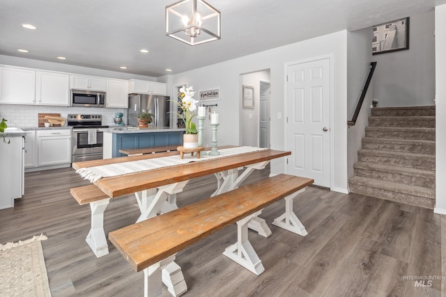 dining space with a notable chandelier, recessed lighting, stairs, and wood finished floors