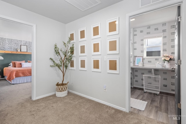 corridor with visible vents, carpet flooring, and baseboards