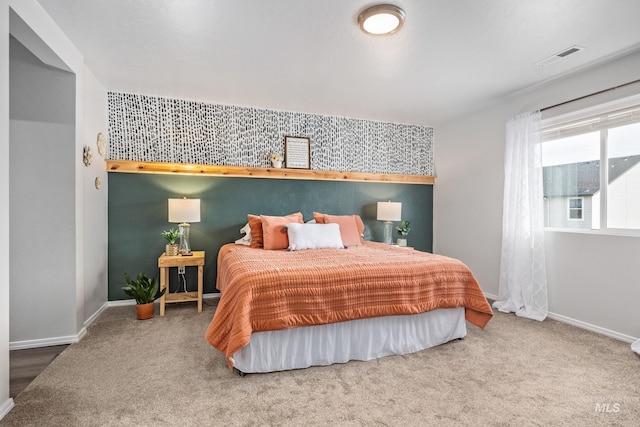 bedroom featuring an accent wall, visible vents, carpet, and baseboards