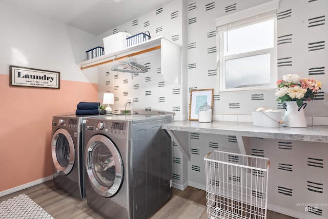 laundry room featuring light wood-type flooring, baseboards, washing machine and dryer, and laundry area