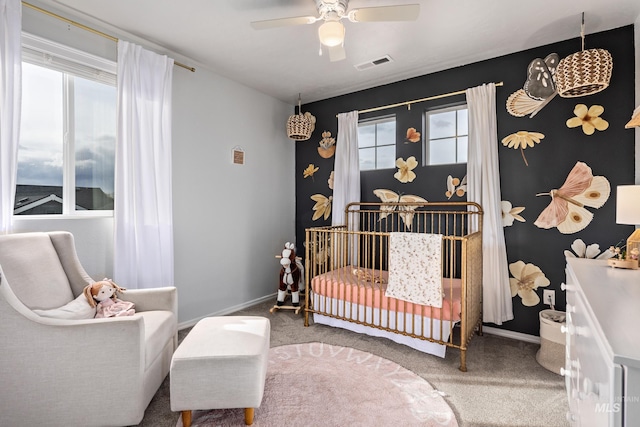 carpeted bedroom with visible vents, ceiling fan, baseboards, and a nursery area