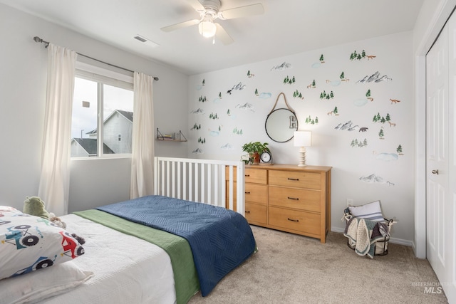 bedroom with visible vents, a closet, baseboards, light colored carpet, and ceiling fan