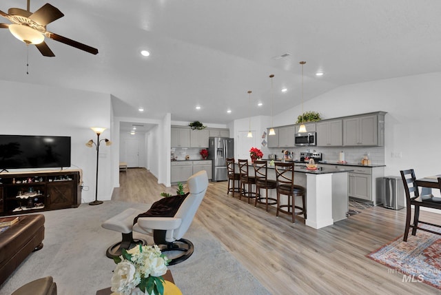 living area with visible vents, light wood finished floors, recessed lighting, ceiling fan, and vaulted ceiling