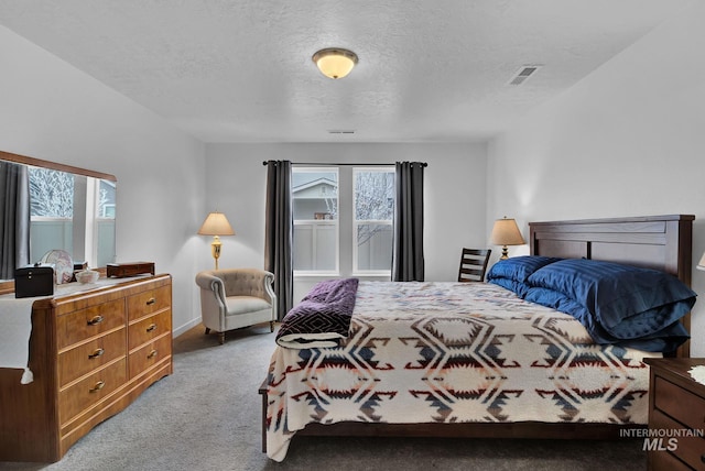 bedroom with visible vents, carpet floors, and a textured ceiling