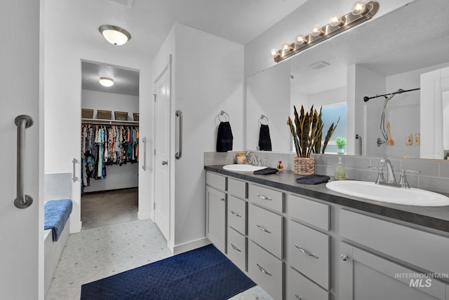 bathroom with double vanity, a spacious closet, backsplash, and a sink