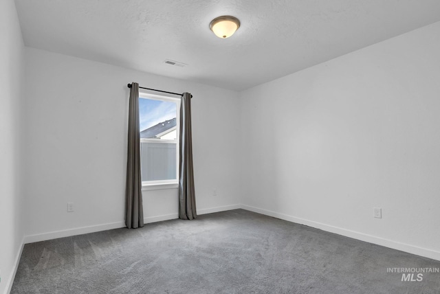 carpeted empty room with visible vents, a textured ceiling, and baseboards