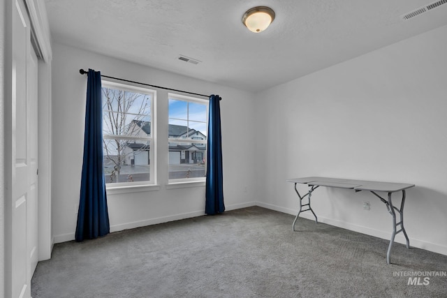 empty room with visible vents, baseboards, carpet, and a textured ceiling