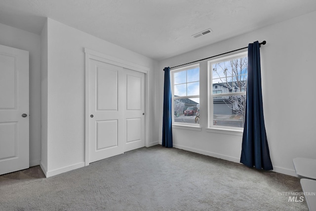 unfurnished bedroom featuring a closet, carpet flooring, baseboards, and visible vents