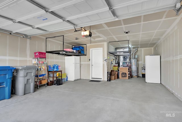 garage featuring water heater, a garage door opener, and freestanding refrigerator