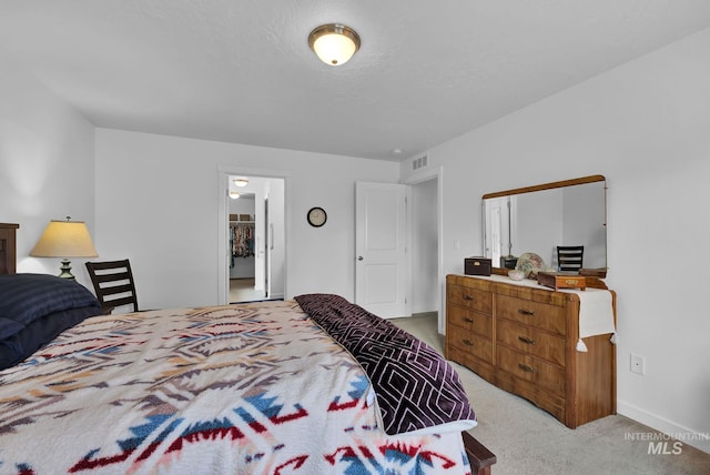 bedroom featuring visible vents, baseboards, light colored carpet, and a textured ceiling