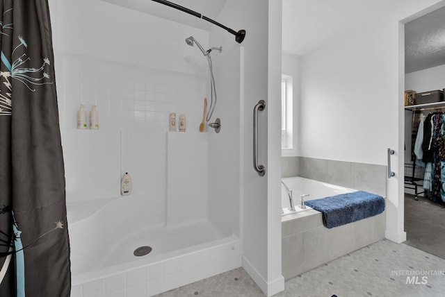 bathroom featuring a walk in closet, a bath, and a tile shower