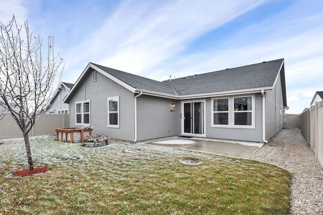 back of property with a yard, a patio area, a fenced backyard, and roof with shingles