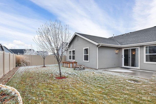 rear view of property featuring a patio area, a lawn, a fenced backyard, and roof with shingles