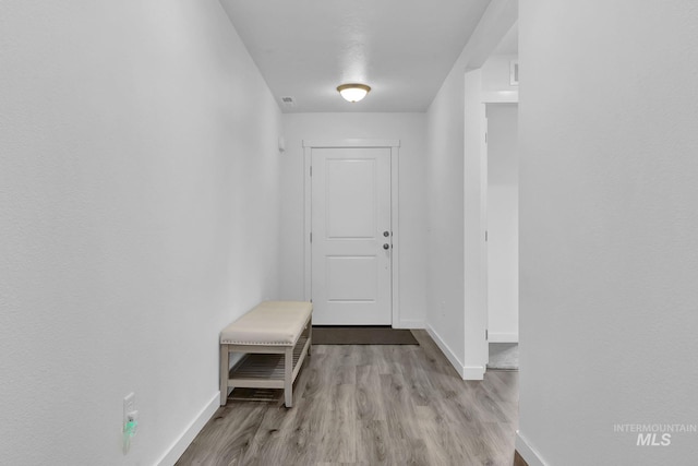 hall featuring visible vents, baseboards, and wood finished floors