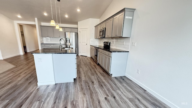 kitchen featuring backsplash, gray cabinets, stainless steel appliances, and wood finished floors