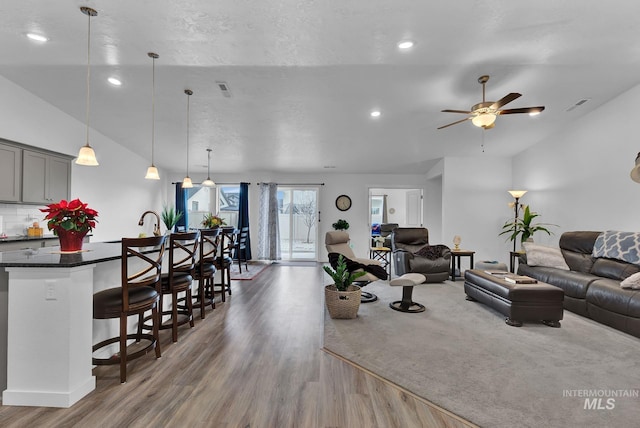 living room with visible vents, recessed lighting, lofted ceiling, and wood finished floors