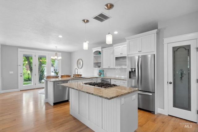 kitchen featuring appliances with stainless steel finishes, open shelves, white cabinetry, a sink, and a peninsula