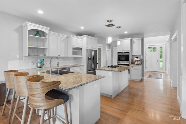 kitchen with appliances with stainless steel finishes, a sink, a peninsula, a kitchen island, and decorative backsplash