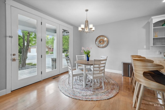 dining room featuring a chandelier, french doors, wood finished floors, and baseboards