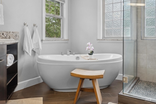 bathroom featuring a shower stall, a freestanding bath, wood tiled floors, and baseboards