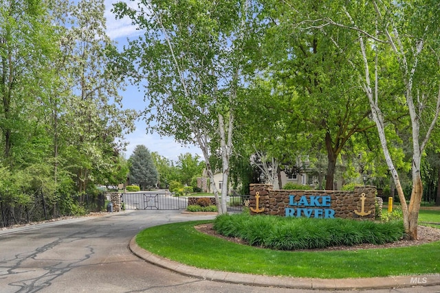 community / neighborhood sign featuring asphalt driveway and a gate