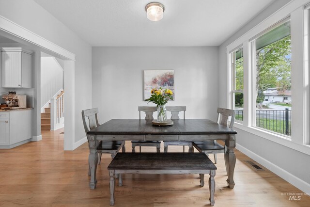 dining space with light wood-style flooring, stairway, and baseboards
