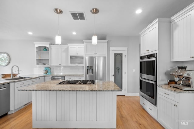 kitchen featuring appliances with stainless steel finishes, a sink, open shelves, light wood-type flooring, and recessed lighting