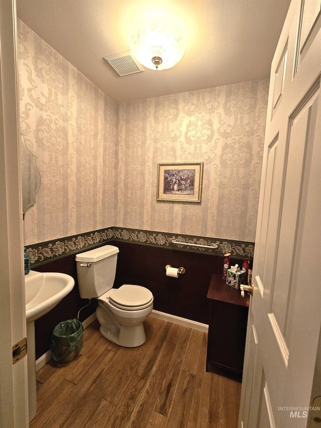 bathroom with hardwood / wood-style flooring, toilet, and a textured ceiling