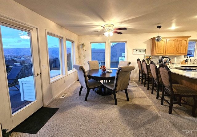 dining room with carpet, a mountain view, and ceiling fan