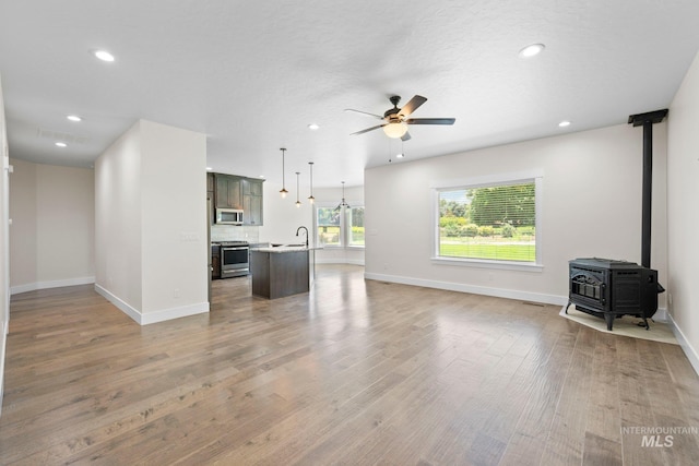 7253 River View Dr, Marsing, ID 83639 - unfurnished living room with a ceiling fan, light wood-style flooring, a wood stove, and recessed lighting