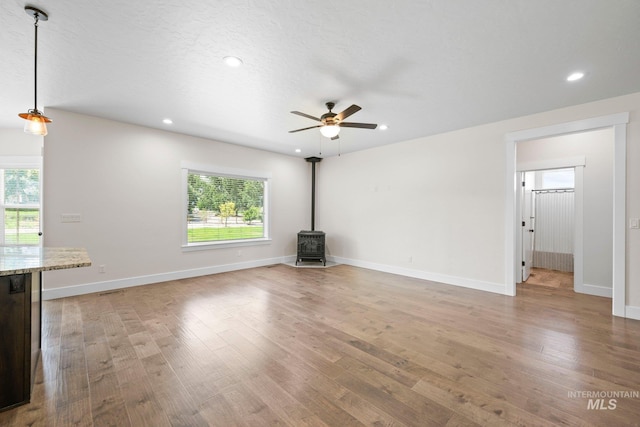 7253 River View Dr, Marsing, ID 83639 - unfurnished living room featuring a wood stove, ceiling fan, light wood-style flooring, healthy amount of natural light, and recessed lighting