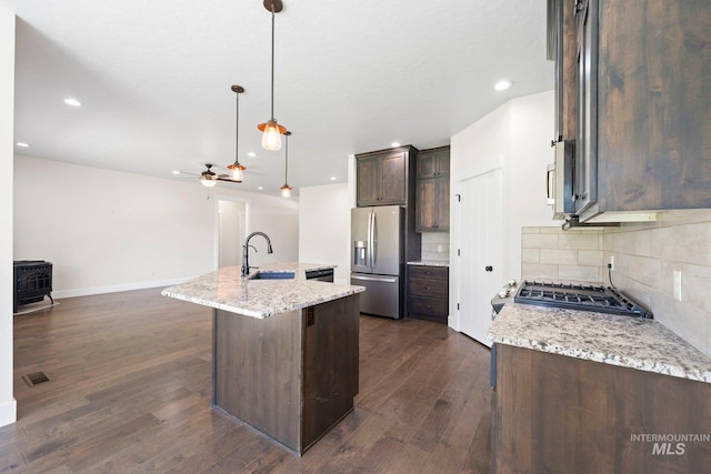 7253 River View Dr, Marsing, ID 83639 - kitchen featuring stainless steel fridge with ice dispenser, a wood stove, dark brown cabinetry, decorative backsplash, and dark wood-style floors