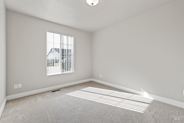 spare room featuring visible vents, baseboards, and carpet