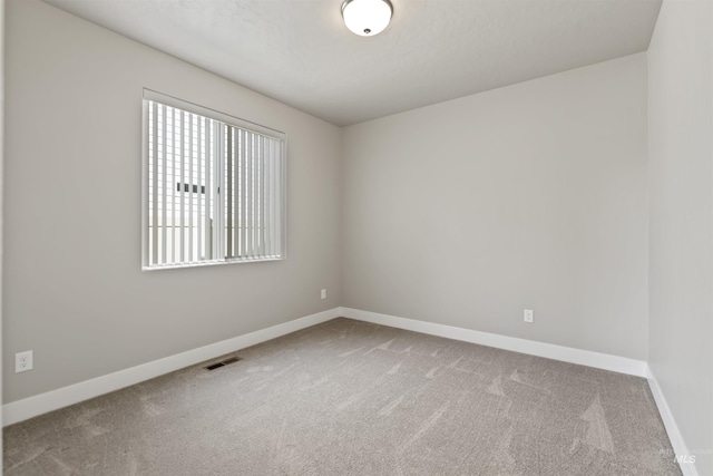 spare room with visible vents, baseboards, and carpet flooring